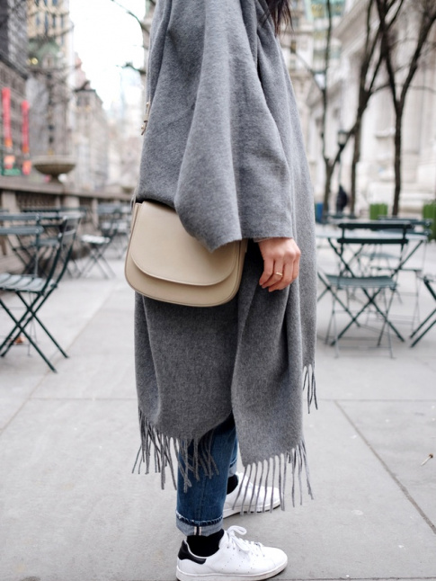 Port avec une paire de baskets blanches, le maxi poncho gris devient plus urbain que folk