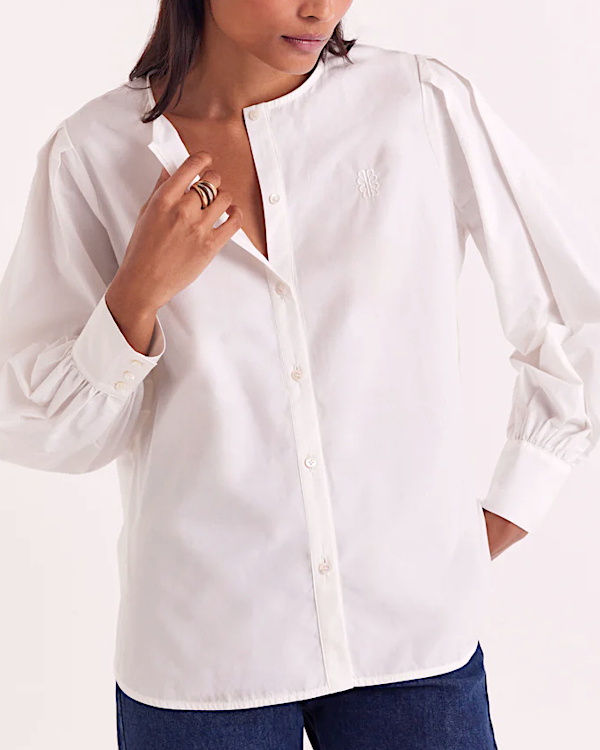 Blouse blanche épurée à manches longues et col rond portée avec un jean brut