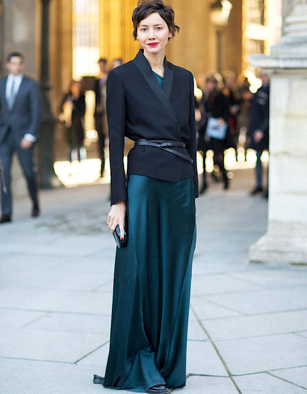 Longue robe satinée vert profond portée avec une veste noire ceinturée