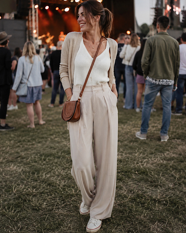 Femme en tenue beige fluide avec pantalon large et sac bandoulière à un festival